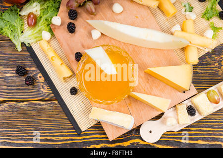 High Angle View of Gourmet Cheese and Fruit Board with Dish of Fruit Preserves for Dipping and Variety of Cheese Wedges with Copy Space on Rustic Wooden Table. Stock Photo