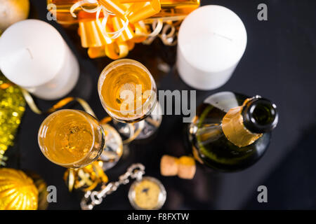 High Angle View of Bottle of Champagne and Glasses on Table with White Candles, Pocket Watch and Gold Christmas Gift and Decorations. Stock Photo
