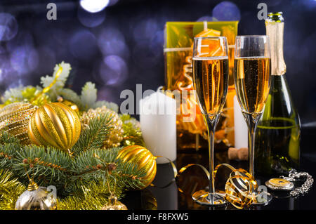 Festive Still Life - Two Glasses of Sparkling Champagne with Bottle, Candles, Gifts and Christmas Decorations on Black Background. Stock Photo