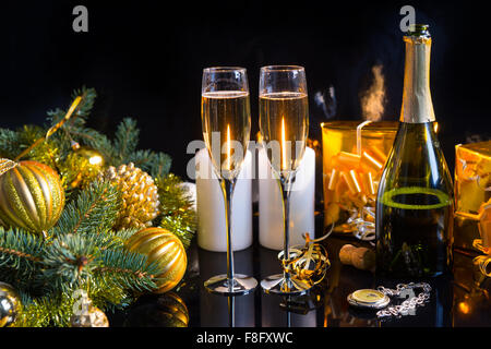 Festive Still Life - Two Glasses of Sparkling Champagne with Bottle, Candles, Gifts, Pocket Watch and Christmas Decorations on Black Background. Stock Photo