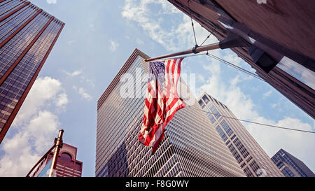Vintage toned American flag and skyscrapers in Manhattan, New York City, USA. Stock Photo