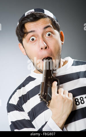 Prisoner with gun against dark background Stock Photo