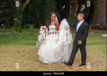 Groom assisting by carrying the bride's train Stock Photo