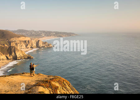 Caucasian couple on cliff admiring seascape Stock Photo