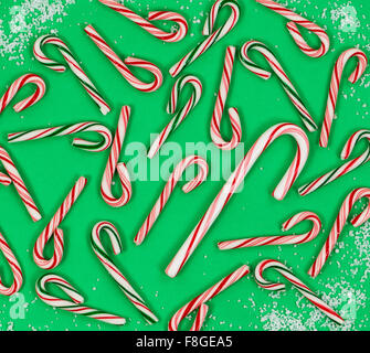 High angle shot of various candy canes and light snow on green background. Holiday concept with filled frame layout. Stock Photo
