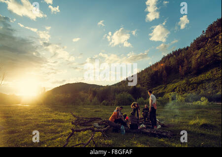 Men and woman with camping accessories standing in field Stock