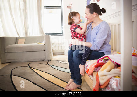 Mother and daughter sitting on bed Stock Photo