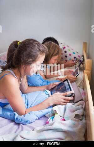 Girls using digital tablets on bed Stock Photo