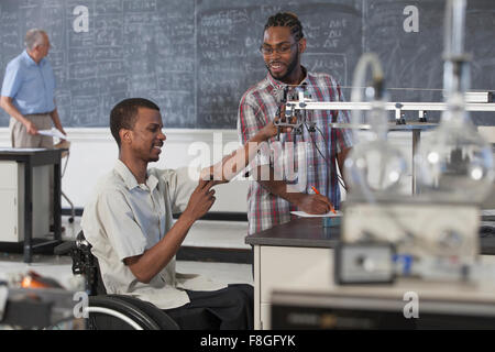 Paraplegic student working with classmate in science classroom Stock Photo