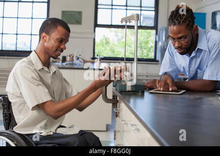 Paraplegic student and classmate working in science classroom Stock Photo