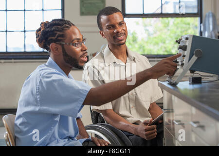 Paraplegic student and classmate working in science classroom Stock Photo