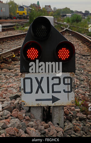 A low level shunting signal in a sidings showing two red lights and with a number plate for identification under the signal head Stock Photo