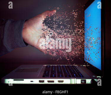Pixelated hand of Caucasian man dissolving into laptop screen Stock Photo