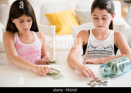 Caucasian twin sisters counting savings Stock Photo