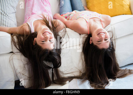 Caucasian twin sisters laying on sofa Stock Photo