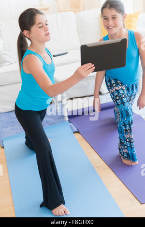 Caucasian twin sisters learning yoga with digital tablet Stock Photo