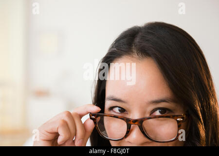 Chinese woman peering over eyeglasses Stock Photo