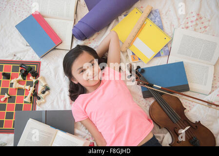 Girl laying on floor with hobbies and homework Stock Photo