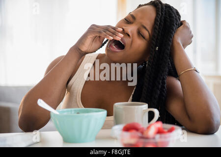 Black woman yawning at table Stock Photo