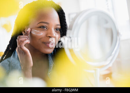 Black woman moisturizing her face Stock Photo