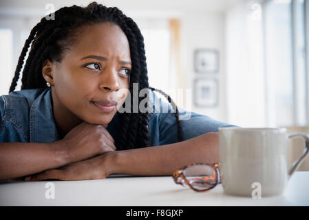 Anxious Black woman resting chin on hands Stock Photo