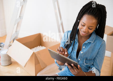 Black woman using digital tablet in new home Stock Photo