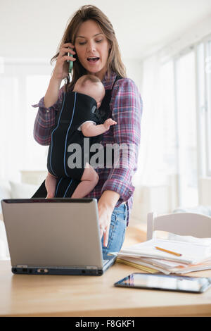 Mother working at home with new baby daughter Stock Photo