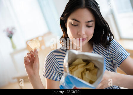 Hispanic woman reading ingredients on bag of potato chips Stock Photo
