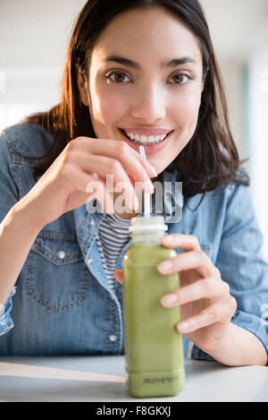 Hispanic woman drinking green juice Stock Photo