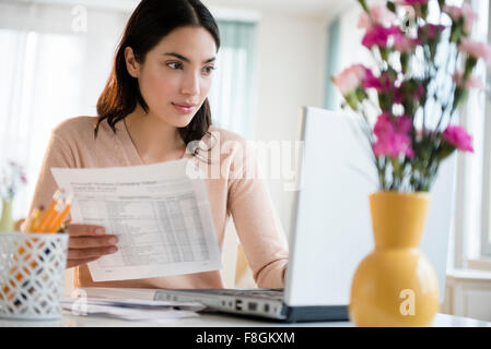 Hispanic woman paying bills on laptop Stock Photo