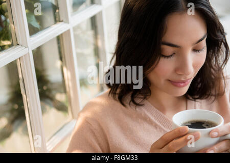 Hispanic woman drinking cup of coffee Stock Photo