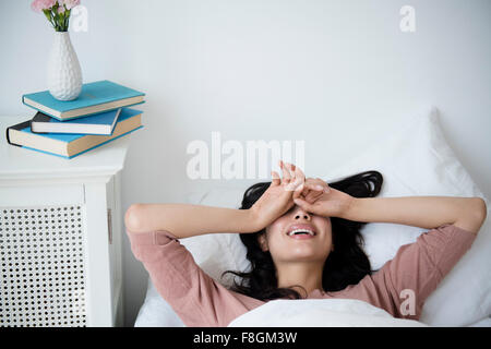Hispanic woman waking up in bed Stock Photo