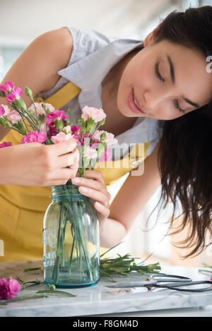 Hispanic woman arranging bouquet of flowers Stock Photo