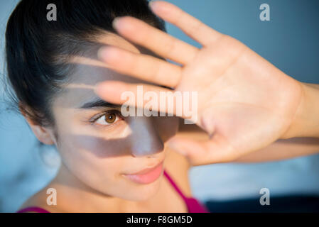 Hispanic woman shielding herself from light Stock Photo