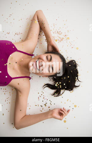 Hispanic woman laying in confetti Stock Photo