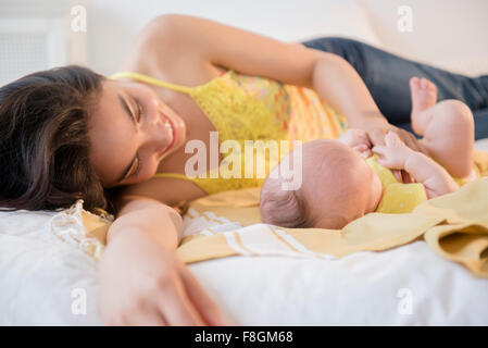 Mother playing with baby daughter on bed
