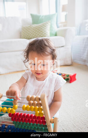 Mixed race baby girl playing with abacus Stock Photo
