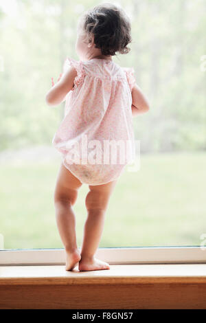 Mixed race girl looking out window Stock Photo