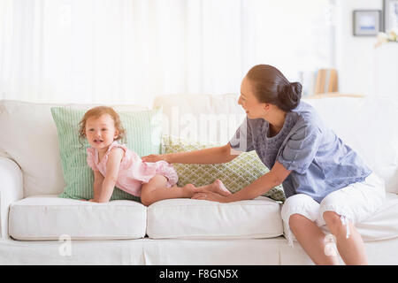 Mother and baby daughter playing on sofa Stock Photo