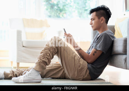 Asian man using cell phone in living room Stock Photo