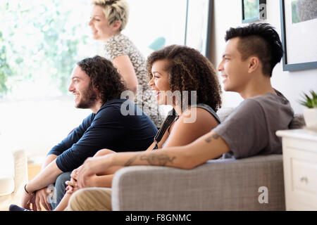 Friends watching television on sofa
