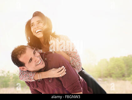 Hispanic man carrying girlfriend piggyback Stock Photo