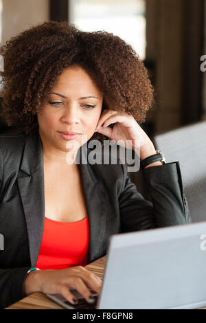 Mixed race businesswoman working on laptop Stock Photo