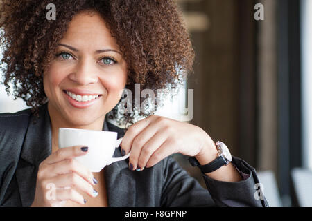 Mixed race woman drinking coffee in cafe Stock Photo