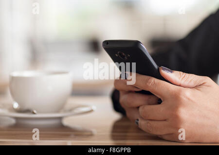 Close up of mixed race woman using cell phone in cafe Stock Photo