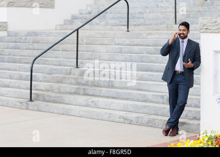 Indian businessman talking on cell phone by steps Stock Photo