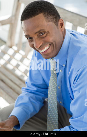 Black businessman smiling on bench Stock Photo