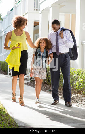 Parents walking daughter to school Stock Photo