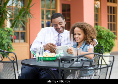 Father and daughter eating at outdoor restaurant table Stock Photo