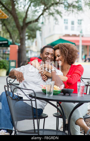 Couple hugging at outdoor restaurant table Stock Photo